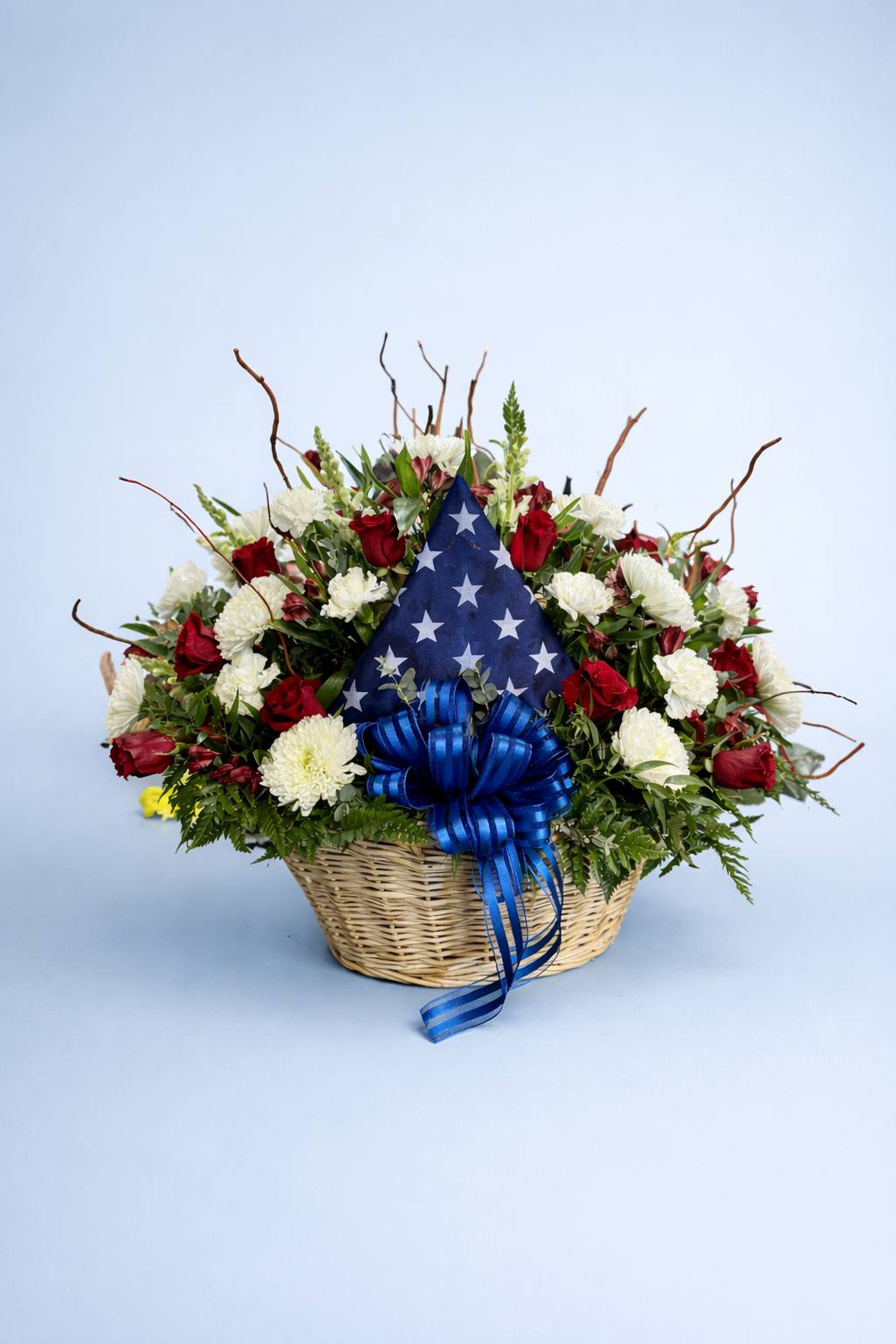 Patriotic red, white, and blue floral arrangement with American flag