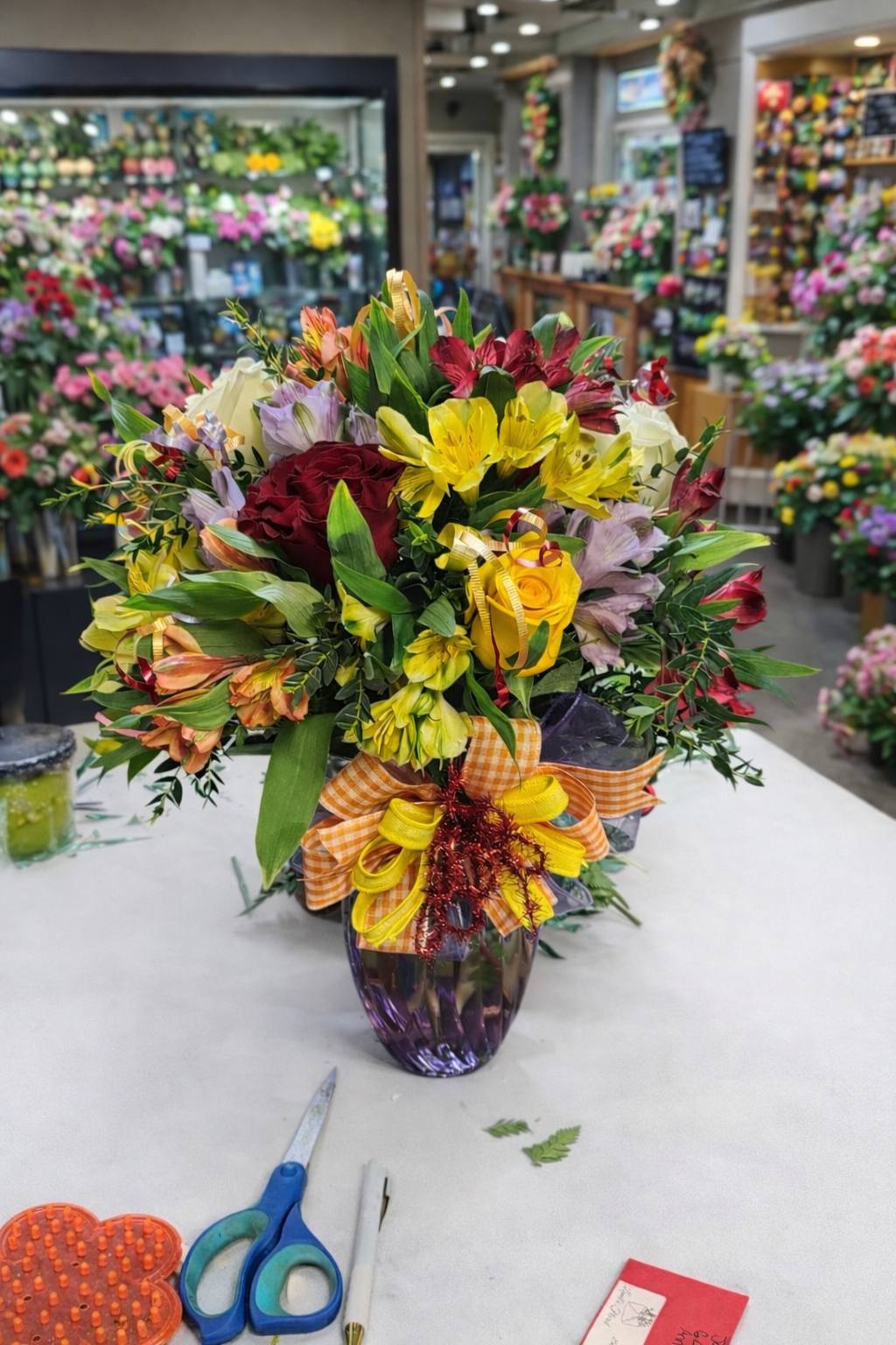 Colorful mixed bouquet with yellow roses and alstroemeria in purple vase